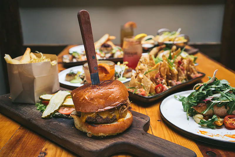 Cheeseburger with fries, nachos and shareable plates on a restaurant table