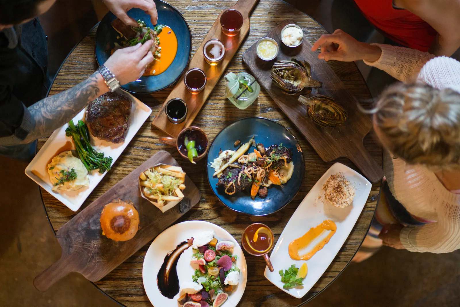 Guests reaching for an overhead spread of entrées, salads, sliders, sides and drinks